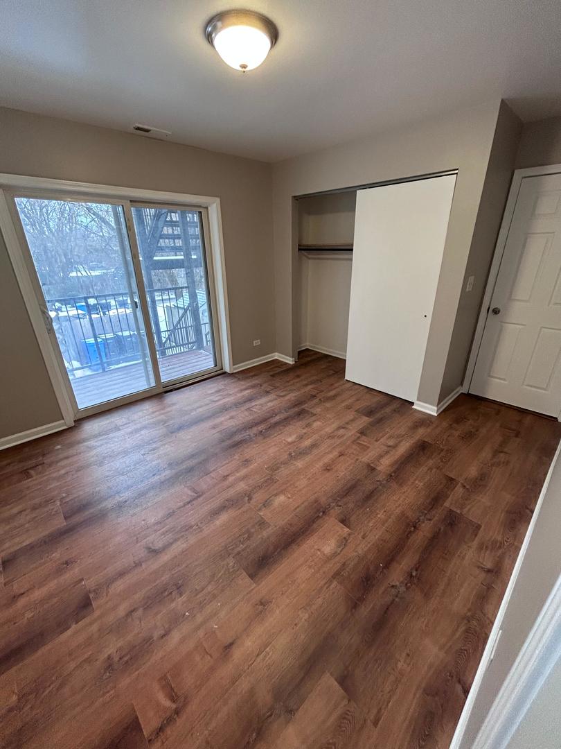 5905 South Indiana Avenue, Unit 1 Chicago, IL 60637 - Photo 4 of 13 an empty room with wooden floor and windows