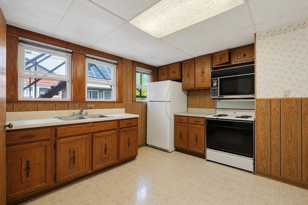 157 Elm Street Somerville, MA 02144 - Photo 12 of 19 a kitchen with stainless steel appliances granite countertop a refrigerator stove and sink