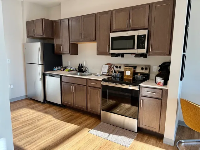 a kitchen with cabinets stainless steel appliances and wooden floor