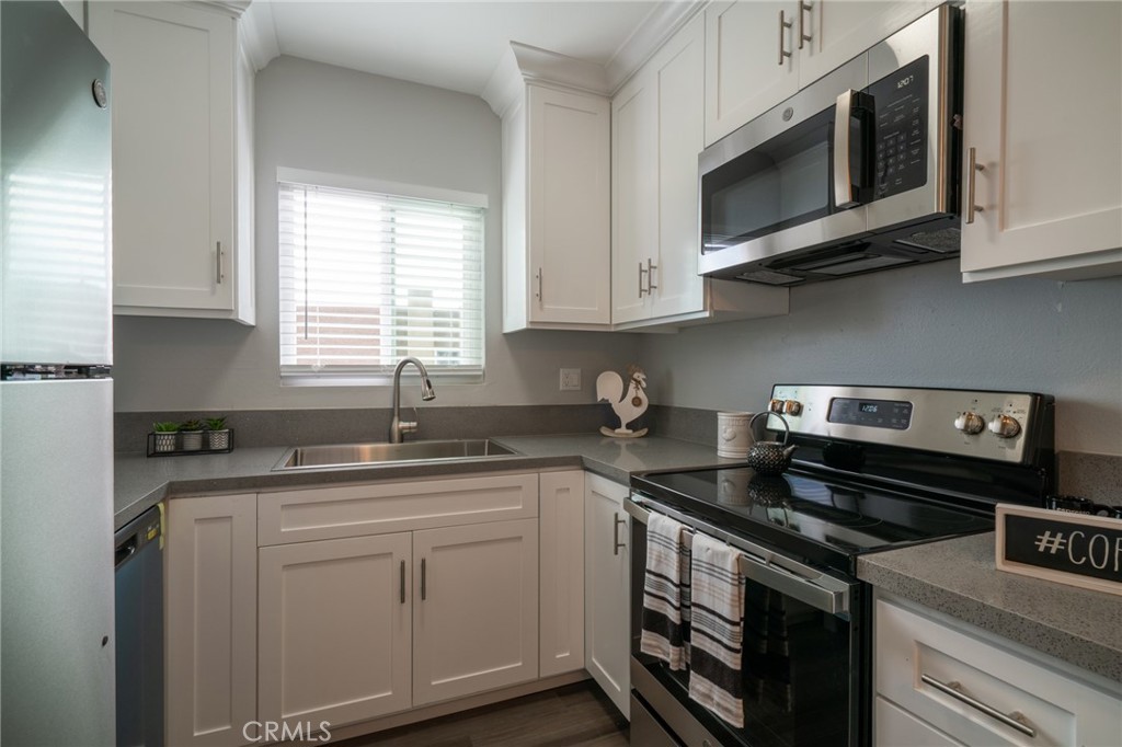 445 Garrison Street Oceanside, CA 92054 - Photo 11 of 12 a kitchen with stainless steel appliances granite countertop white cabinets sink and window