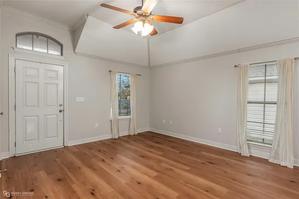 a view of empty room with wooden floor and fan