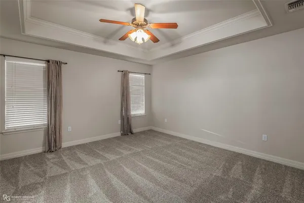 an empty room with a chandelier fan and windows