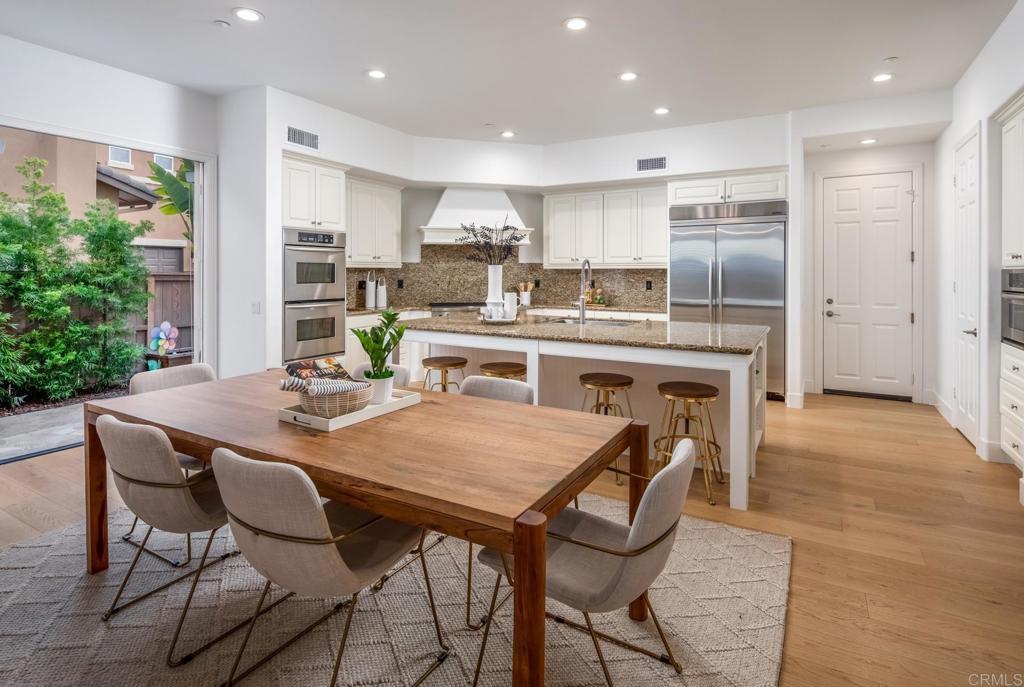 667 Lynwood Drive Encinitas, CA 92024 - Photo 12 of 36 a kitchen with stainless steel appliances granite countertop a dining table chairs refrigerator and sink