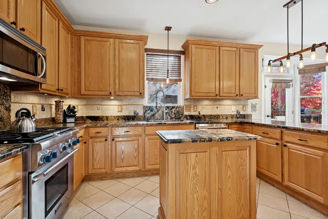 a kitchen with stainless steel appliances granite countertop a sink stove and cabinets