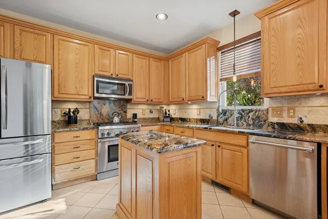 a kitchen with granite countertop white cabinets and stainless steel appliances