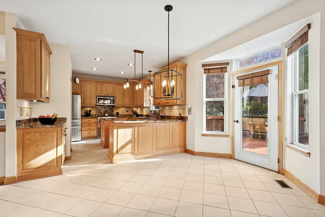 a view of a kitchen with kitchen island granite countertop a refrigerator a stove a sink a dining table and chair