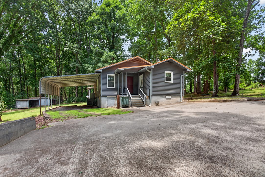 230 Dickard Road Seneca, SC 29672 - Photo 3 of 25 A welcoming home nestled in lush greenery, offering convenient covered parking and a tranquil setting.