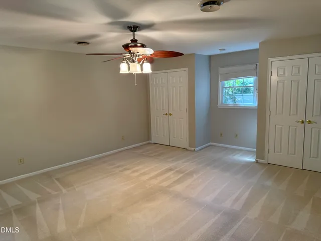 an empty room with a window and a chandelier fan