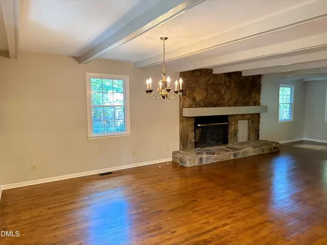 a view of a livingroom with a fireplace wooden floor and windows