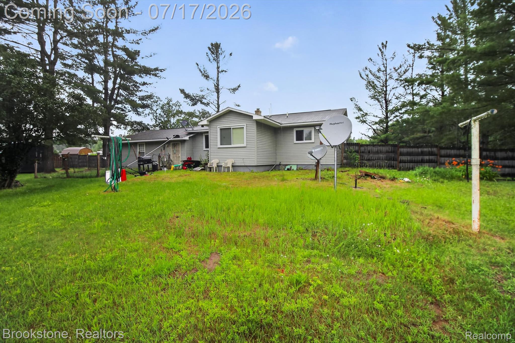 22709 Pleasant Valley Road Hillman, MI 49746 - Photo 34 of 42 Expansive rear yard featuring a large grassy area, mature trees, and a privacy fence
