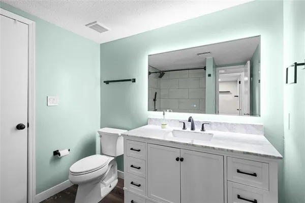 a bathroom with a granite countertop toilet a sink and a mirror