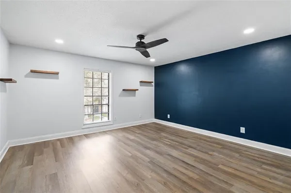 an empty room with wooden floor chandelier fan and windows