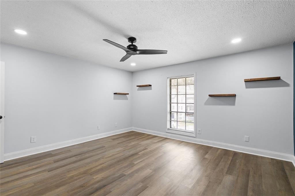 6851 Roswell Road, Unit N10 Atlanta, GA 30328 - Photo 20 of 26 an empty room with wooden floor ceiling fan and windows