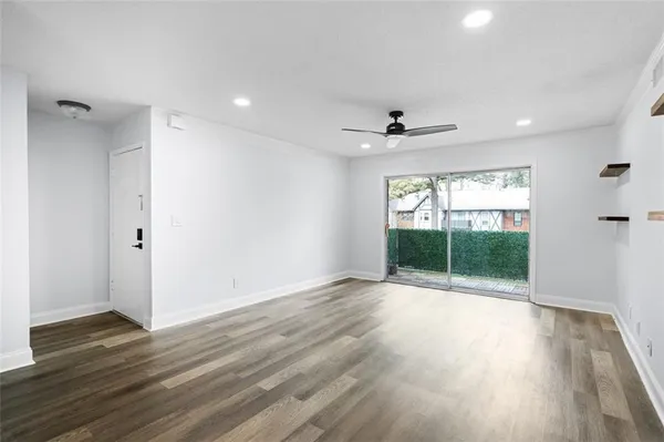 a view of an empty room with wooden floor and a window