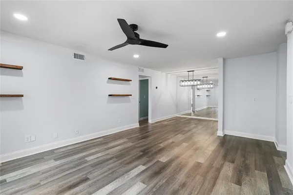 an empty room with wooden floor cabinet and windows