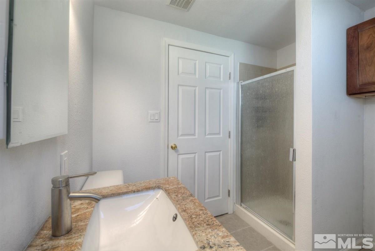 1645 Wyoming Avenue Reno, NV 89503 - Photo 23 of 28 a bathroom with a granite countertop sink a mirror and shower