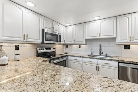 a kitchen with kitchen island granite countertop a sink dishwasher stove top oven and cabinets