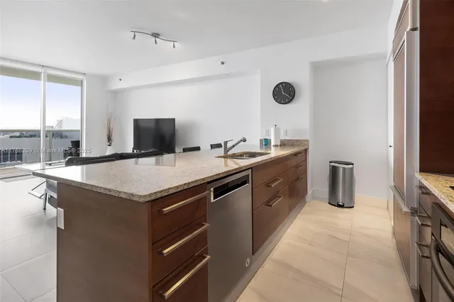 a kitchen with a sink a counter top space a flat screen tv and a window