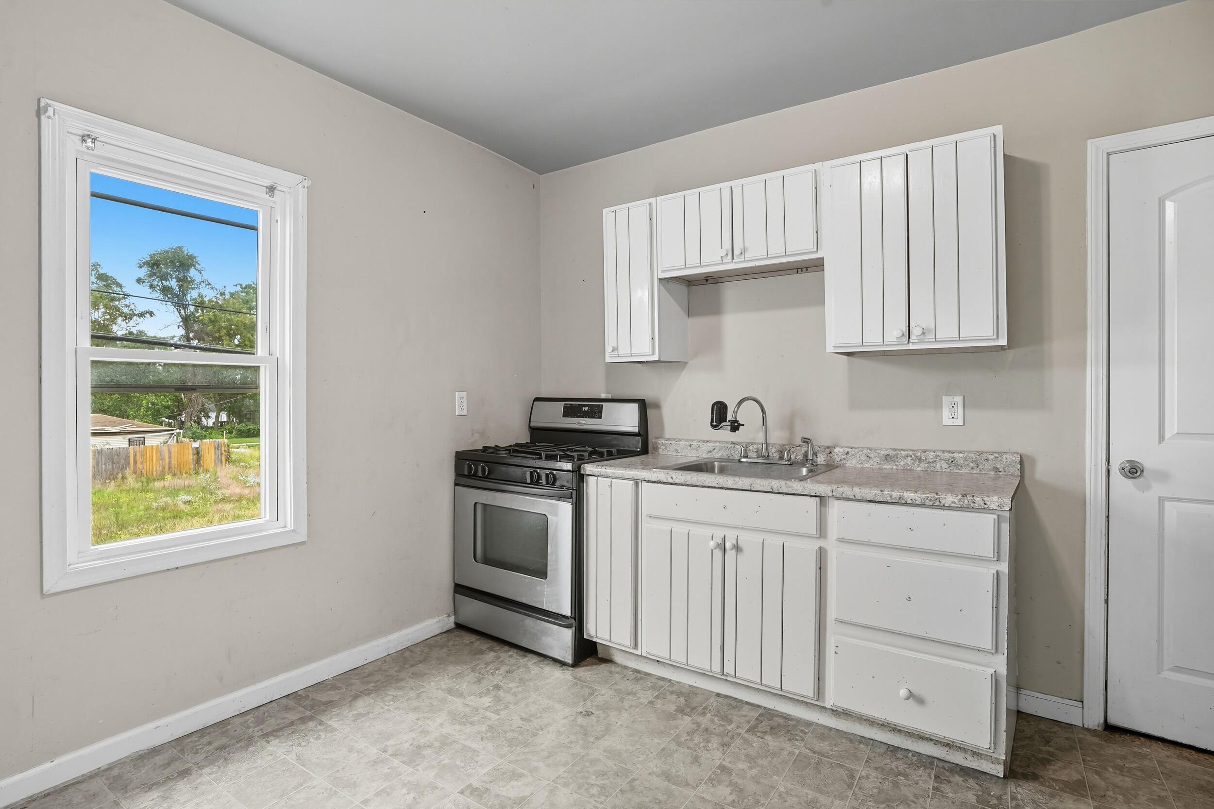 4001 Virginia Street Gary, IN 46409 - Photo 5 of 12 a kitchen with granite countertop white cabinets and window