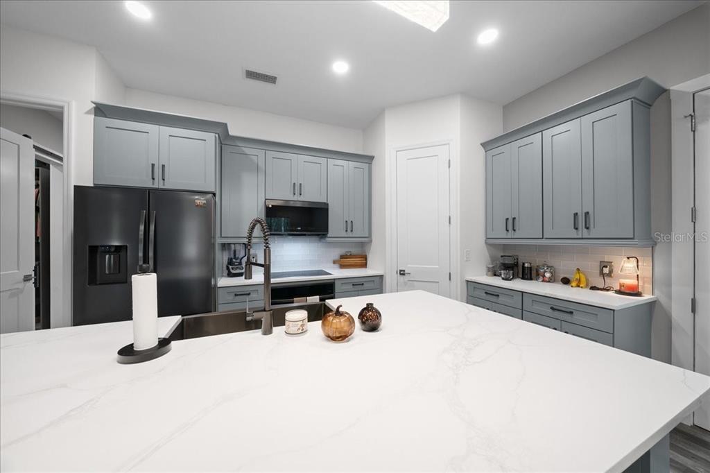 252 Malauka Road Ocklawaha, FL 32179 - Photo 21 of 78 a kitchen with a refrigerator a stove a microwave and wooden cabinets