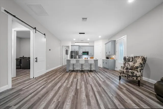 a kitchen with kitchen island a stove a refrigerator a sink a dining table and chairs with wooden floor