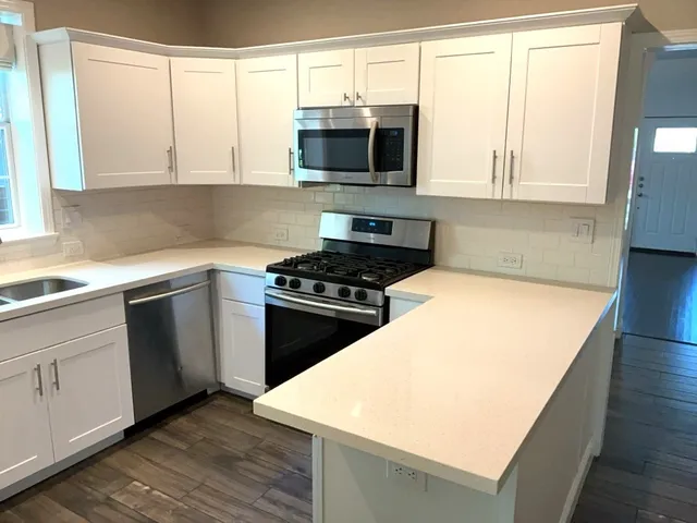 a kitchen with stainless steel appliances a white stove top oven cabinets and a window