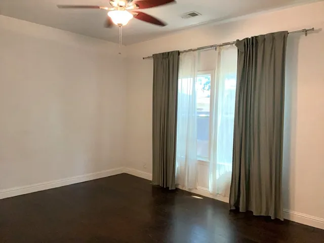 an empty room with wooden floor door and windows