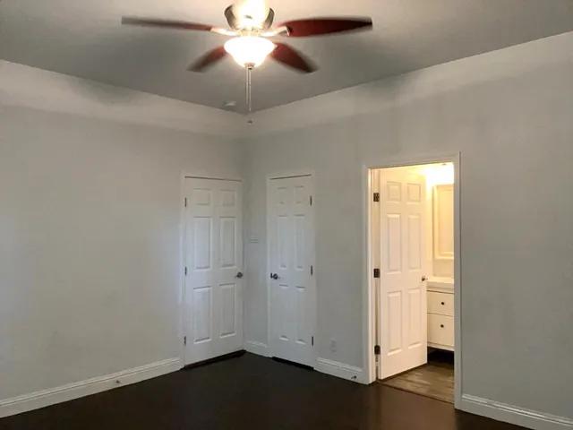 an empty room with wooden floor a ceiling fan and closet area
