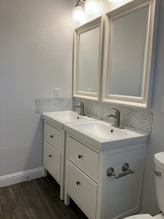 806 East 3rd Street Georgetown, TX 78626 - Photo 9 of 16 Half bath featuring a textured wall, vanity, dark wood-style flooring, and decorative backsplash