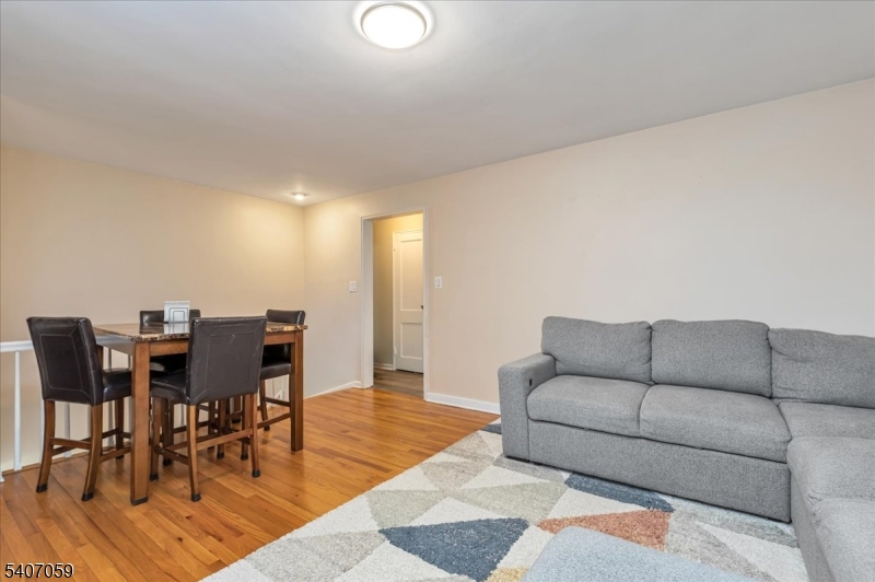445 Morris Avenue, Unit 4C Springfield, NJ 07081 - Photo 17 of 19 a living room with furniture and a dining table with wooden floor