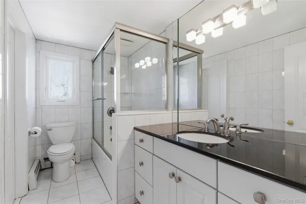a spacious bathroom with a double vanity sink toilet mirror and shower