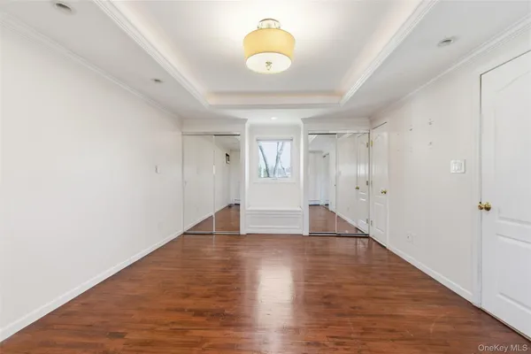 a view of an empty room with wooden floor and window