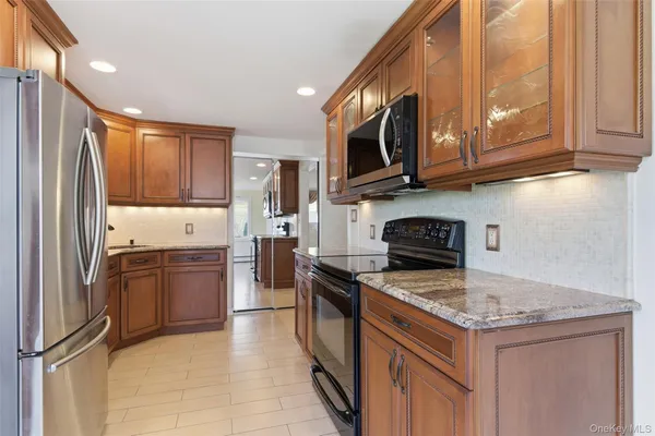 a kitchen with stainless steel appliances granite countertop a stove top oven a sink and a refrigerator