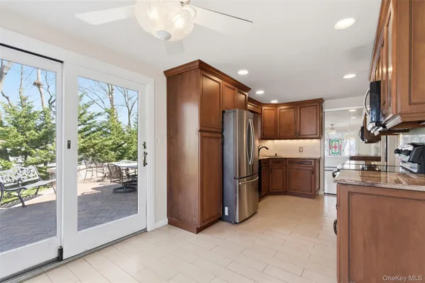 a kitchen with stainless steel appliances granite countertop a refrigerator and a view of living room