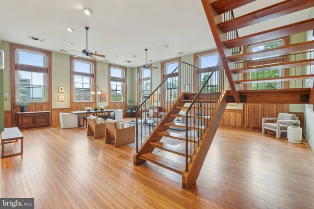 a living room with couches chairs and kitchen view with wooden floor