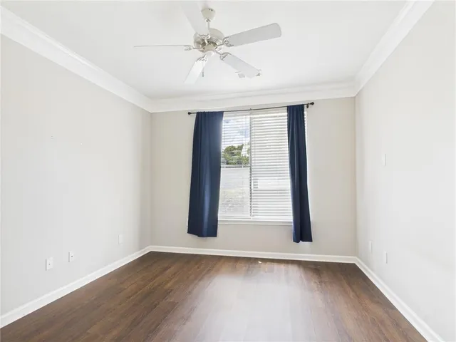 an empty room with wooden floor and fan