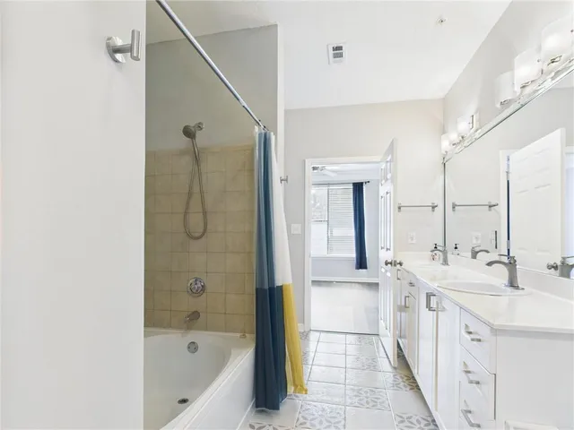 a bathroom with a double vanity sink a tub and mirror