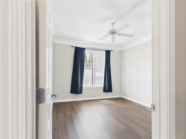 an empty room with wooden floor chandelier fan and windows
