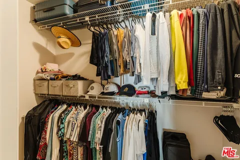 a view of walk in closet with clothes and shoes