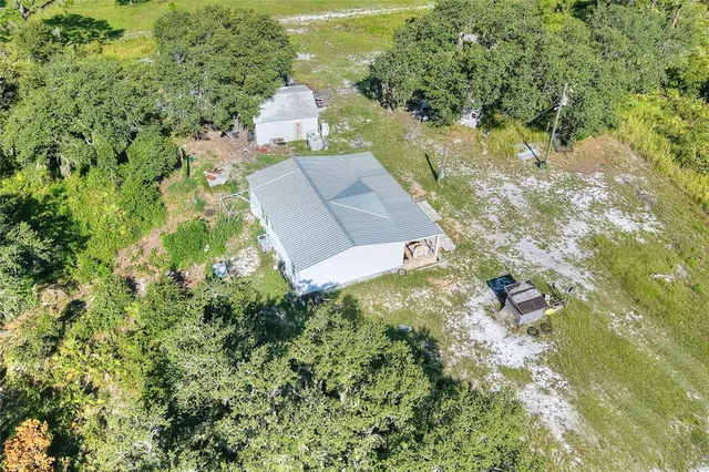 an aerial view of residential house with outdoor space and trees all around