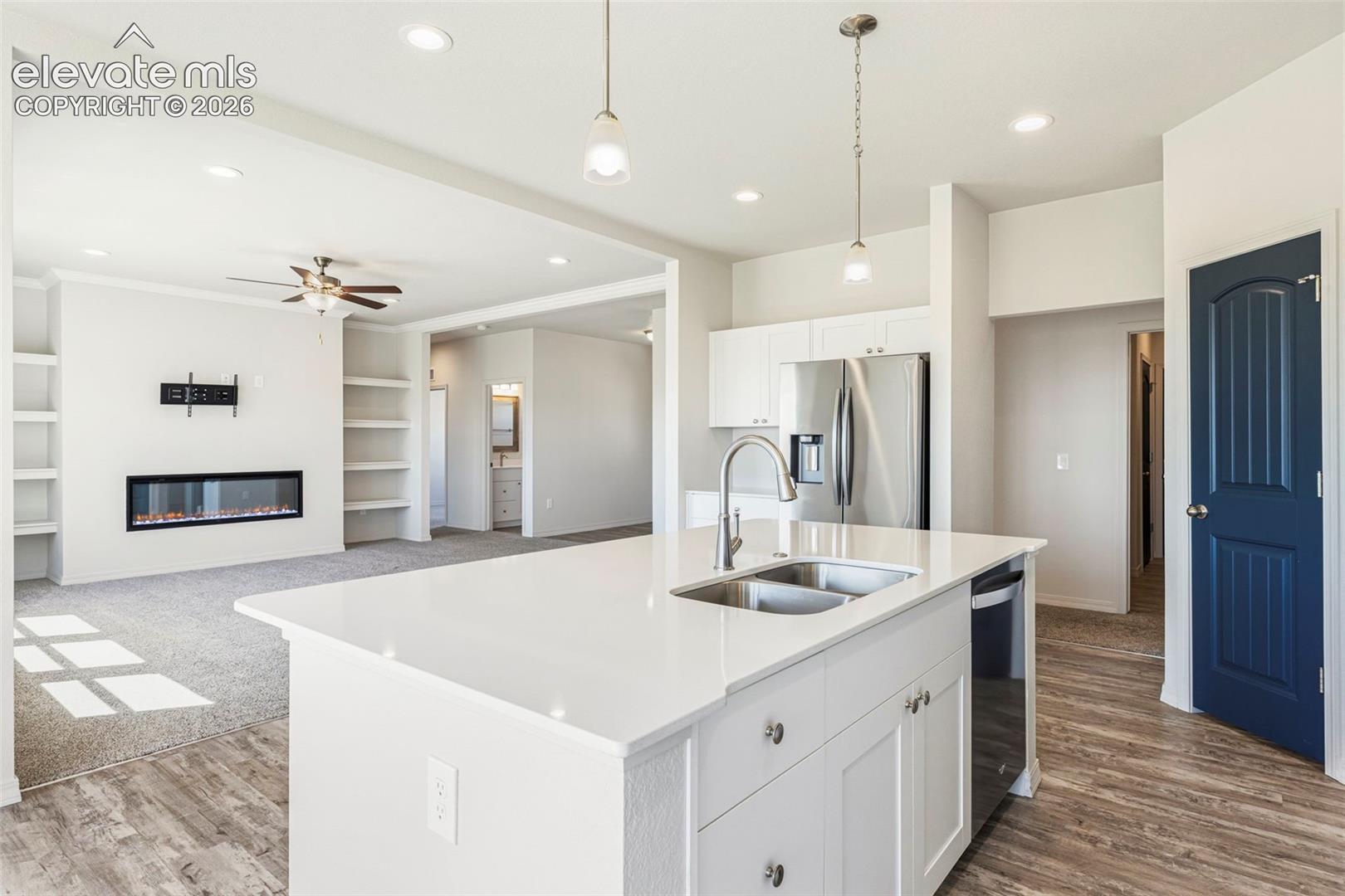 3955 North Yoder Road Yoder, CO 80864 - Photo 15 of 38 Kitchen island with dual stainless steel sink, white cabinetry, and quartz countertop