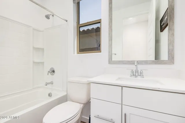 a bathroom with a toilet sink vanity tub and mirror