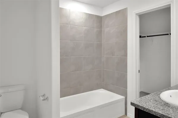 a bathroom with a granite countertop bathtub shower and toilet