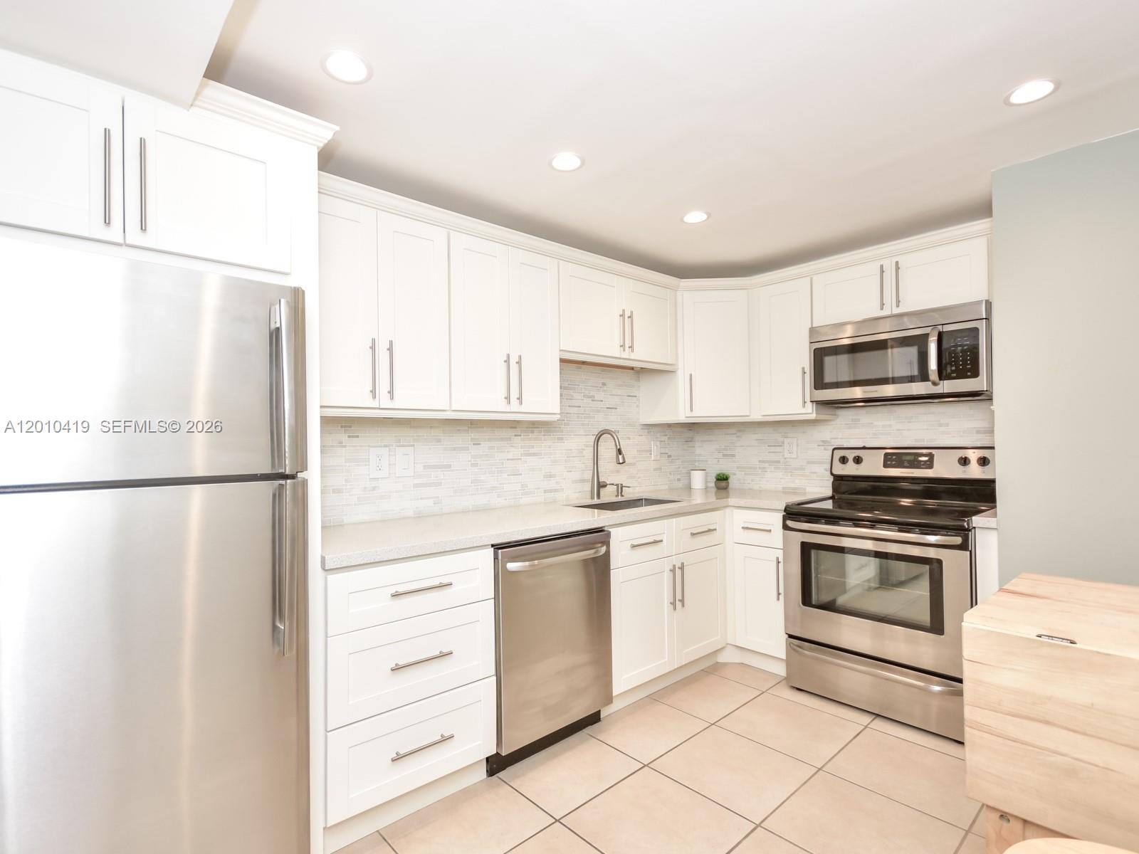 780 Northeast 69th Street, Unit 1908 Miami, FL 33138 - Photo 3 of 18 a kitchen with stainless steel appliances granite countertop white refrigerator stove a sink and a microwave
