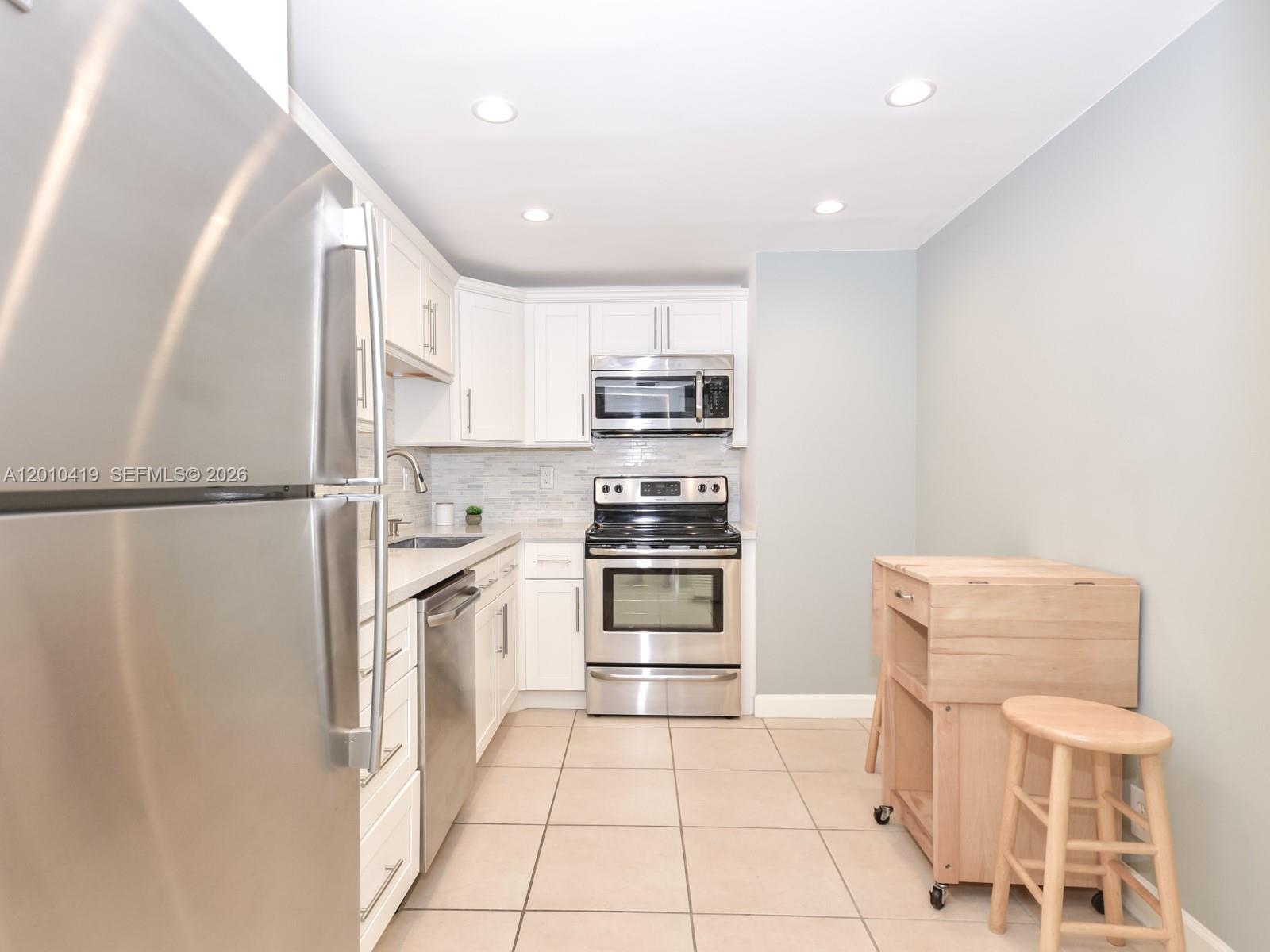 780 Northeast 69th Street, Unit 1908 Miami, FL 33138 - Photo 4 of 18 a kitchen with granite countertop a refrigerator and a stove top oven