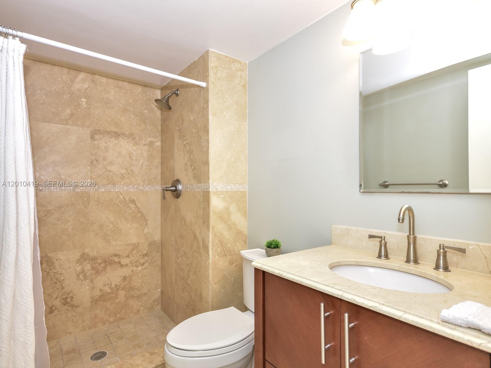780 Northeast 69th Street, Unit 1908 Miami, FL 33138 - Photo 9 of 18 a bathroom with a granite countertop sink toilet a mirror a shower and a sink
