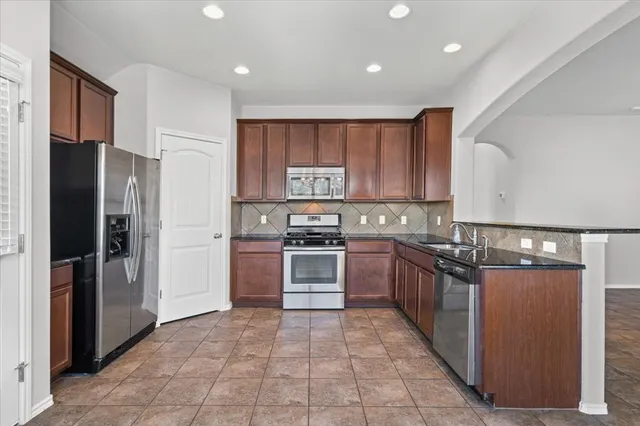 a kitchen with stainless steel appliances granite countertop a refrigerator and a stove top oven