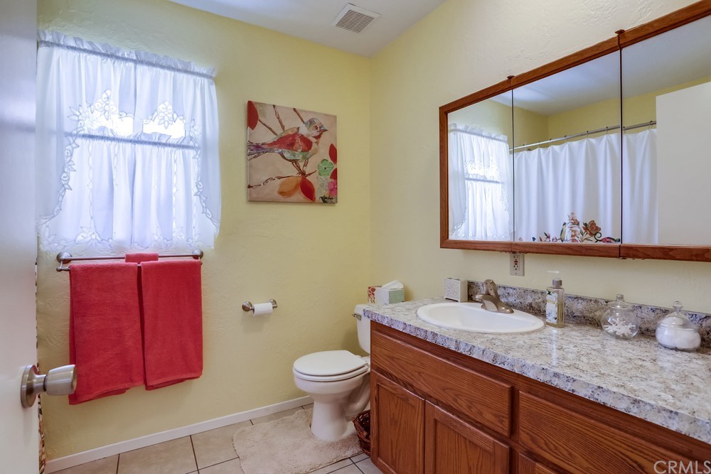 2725 Alta Vista Drive Fallbrook, CA 92028 - Photo 39 of 50 a bathroom with a granite countertop sink a toilet and a mirror