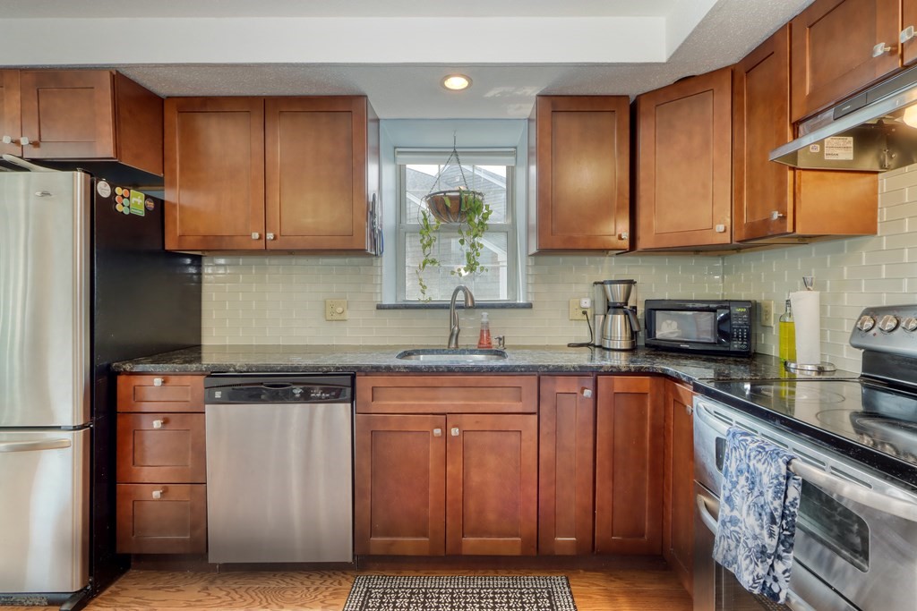 106 Shaw Farm Road, Unit 106 Canton, MA 02021 - Photo 8 of 27 a kitchen with stainless steel appliances granite countertop wooden cabinets a stove a sink and a refrigerator