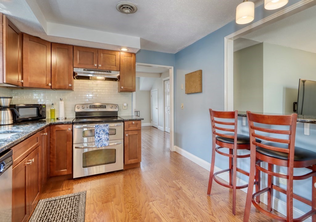 106 Shaw Farm Road, Unit 106 Canton, MA 02021 - Photo 9 of 27 a kitchen with stainless steel appliances wooden cabinets and a stove top oven